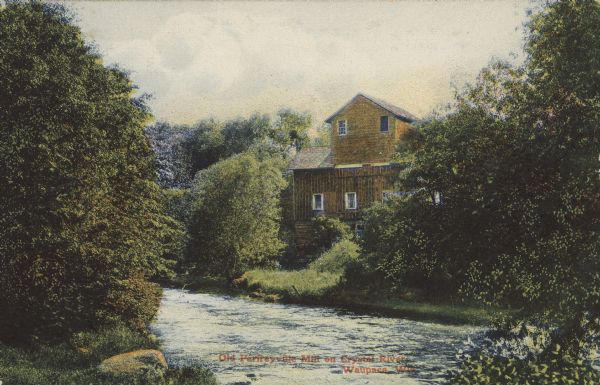 Text on front reads: "Old Parfreyville Mill on Crystal River. Waupaca, Wis." A wooden mill on the banks of a river with a grass and tree covered shoreline.