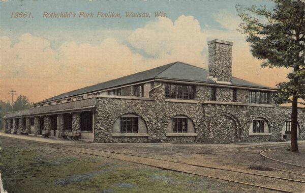 Text on front reads: "Rothchild's Park Pavilion, Wausau, Wis." The Prairie School style stone building was built in 1911. Street car tracks can be seen on two sides. It has been the location for many events and is still in use today.