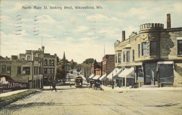 Text on front reads: "North Main St. looking West, Wauwatosa, Wis." Streetcars on an unpaved street with horse-drawn vehicles and pedestrians. The street is lined with sidewalks and businesses. A fence on the left reads: "Pabst."