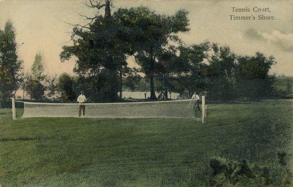 Text on front reads: "Tennis Court, Timmer's Shore." Two men playing tennis on the lawn at a resort on Big Cedar Lake. Trees and the lake are in the background. The resort first opened in 1882 and is still in operation today.