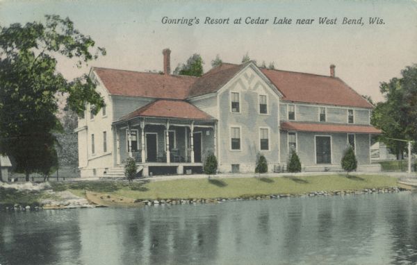 Text on front reads: "Gonring's Resort at Cedar Lake near West Bend, Wis." Two-story clapboard lodging with a covered porch on the left. A rowboat is pulled up onto the shore of Cedar Lake in the foreground.