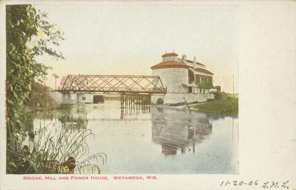 Text on front reads: "Bridge, Mill and Power House, Weyauwega, Wis." The Weyauwega Mill and grain elevator on the right, power house on the left with the Mill Street bridge over the Waupaca River in the center. In the foreground is the Waupaca River. Records indicate that a newer dam was built here in 1931.