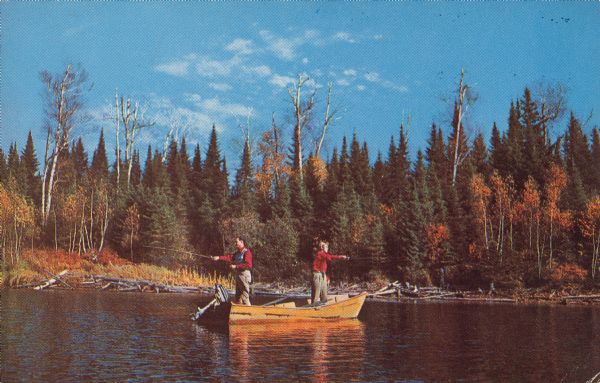 Text on reverse: "Greetings, White Lake, Wis. First Cast of the Day." Two fisherman, facing in opposite directions, cast their lines into the water from a small motorboat. The lake shore is filled with dead tree trunks and branches, and beyond are mainly pine and birch trees.