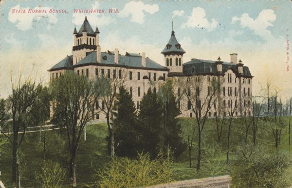 Text on front reads: "State Normal School, Whitewater, Wis." Called "Old Main," this building was built in 1868 and destroyed in a fire in 1970. In the foreground is a lawn on a slope with many trees. The school graduated its first class of teachers in 1870.