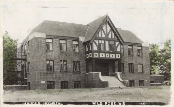Text on front reads: "Hadden Hospital, Wild Rose, Wis." A two-story brick hospital with a full basement and decorative entrance. Established in 1941 by Dr. Shirley Louis Hadden, he was much beloved by his patients. A new hospital was eventually built and is now called "ThedaCare Medical Center-Wild Rose."<p>The post card is addressed to "Gov. O. Rennebohm." The message reads: "Governor ('R"), Thank you so much for your kind and helpfulness to the Wild Rose Hospital Project. It was a pleasure meeting you here in Wild Rose. All Dr. and I can do to help you, you can depend on from both of us. Mrs. S. Hadden."