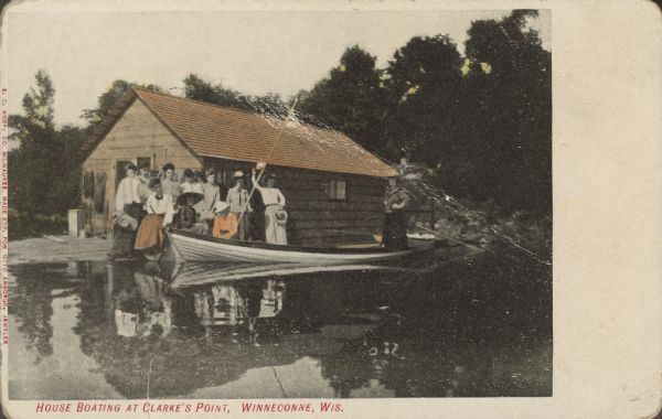 Text on front reads: "House Boating at Clarke's Point, Winneconne, Wis." A group of women posing in and around a canoe in front of a houseboat. In the background are trees. One woman is waving at the photographer. Clarks Point is an unincorporated community located on the eastern shore of Lake Winneconne.