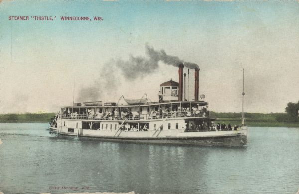 Text on front reads: "Steamer 'Thistle,' Winneconne, Wis." Many passengers pose on the deck of a steamer on Lake Winneconne. The shoreline in the background is tree-lined.