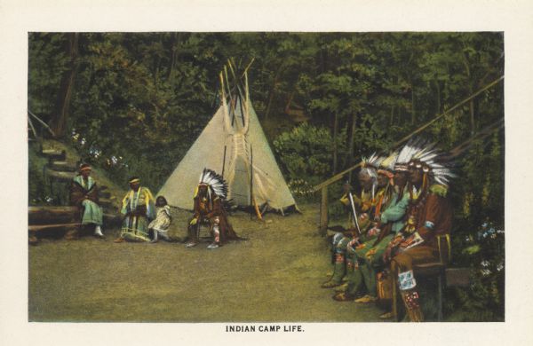 Text reads: "Indian Camp Life." One of 16 postcard images inside of a souvenir view folder. Four Native American men are sitting on a bench on the right. Two Native American women, one girl and one man are seated on the opposite side. They are wearing indigenous dress. A tipi is in the background with staircases of wood and stone to the right and left. Trees and flowers fill the background.