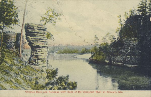 Text on front reads: "Chimney Rock and Romance Cliff, Delle of the Wisconsin River at Kilbourn, Wis." Rock formations and trees line the river, and a sandbar is behind Romance Cliff.<p>Kilbourn City was founded in 1857 by Byron Kilbourn, the name was changed in 1931 to Wisconsin Dells.</p>