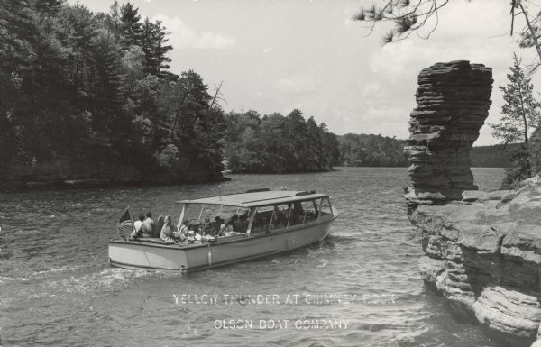 Text on front reads: "Yellow Thunder at Chimney Rock. Olson Boat Company." The tour boat "Yellow Thunder" with visitors viewing Chimney Rock, a formation on the shore of the Wisconsin River. The shoreline is filled with more formations and trees.