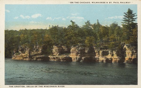Text on the front reads: "'On the Chicago, Milwaukee & St. Paul Railway.' The Grottos, Dells of the Wisconsin River." Rock formations on the shore of the Wisconsin River. Trees are on top of the formations.
