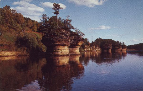 Text on reverse reads: "Ink Stand. One of the Rocky Islands found in the beautiful lower Dells of the Wisconsin River." Rock formations are along the shore with trees growing on the tops.
