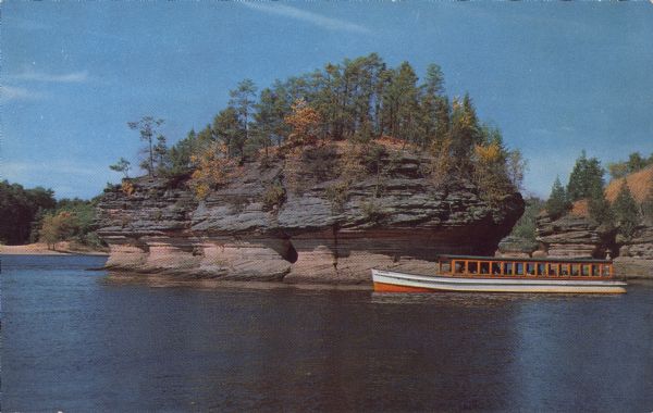 Text on reverse reads: "Lone Rock. Lower Dells of the Wisconsin River. Wisconsin Dells, Wisconsin." A tour boat glides past an island rock formation, with trees and foliage growing on the top.