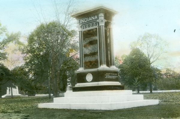 Hand-colored lantern slide of the Indiana Monument at the Andersonville National Cemetery. The monument was made of Montello granite at a cost of $10,000 in 1908 and was dedicated to the Indiana prisoners of war "who for the cause they loved gave up their lives in Andersonville Prison, from February 1864 to April 1865."