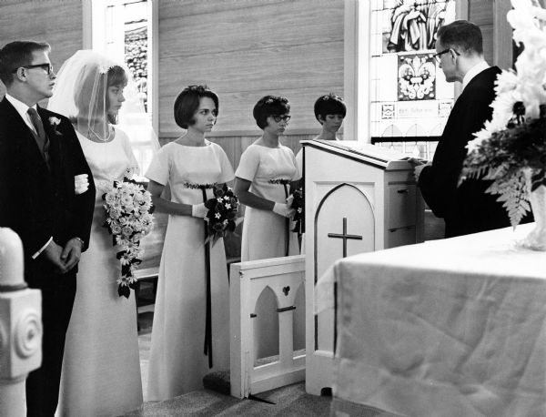 Reverend Hahm officiates at the Rath/Beck wedding. He stands at the altar in front of the bride and groom and three bridesmaids.