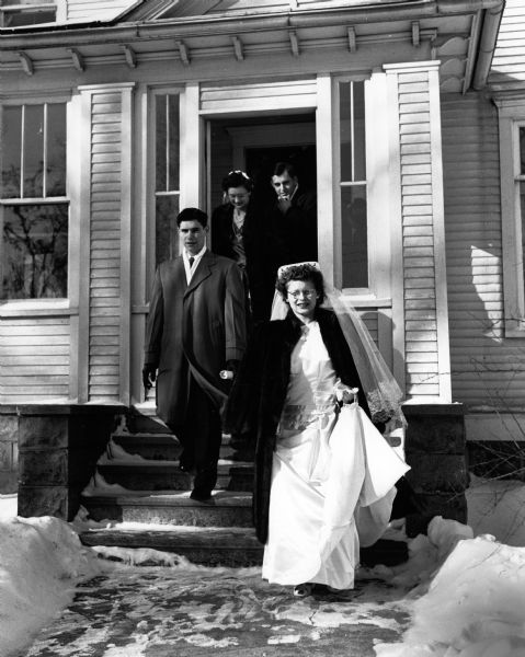The newlyweds with attendants Pearl Ruecker and Tom Hartwig emerge from Father Goff's parsonage at the Catholic Church.