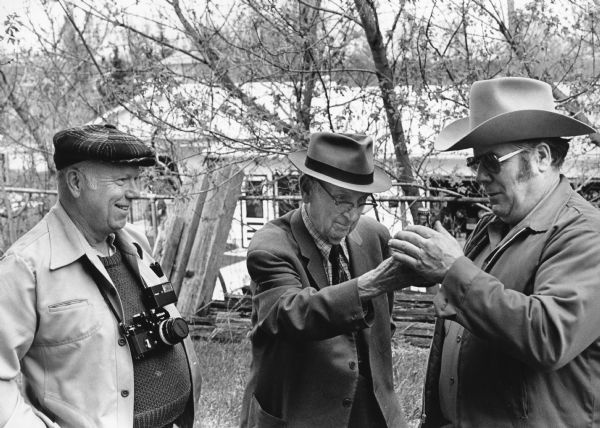 Photographer Edgar Mueller, "Corny" Weber, and auctioneer Ken Schoebel check out an old Weber Beer Bottle.
