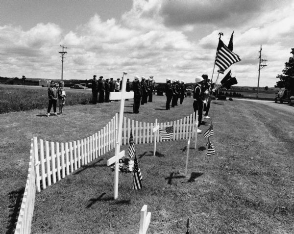Mourners, miltary band, and white crosses on Memorial day.
