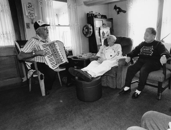 "Justy" Justman entertains Ralph Widmer and his caregiver, Eiko Olson, in Ralph's home.