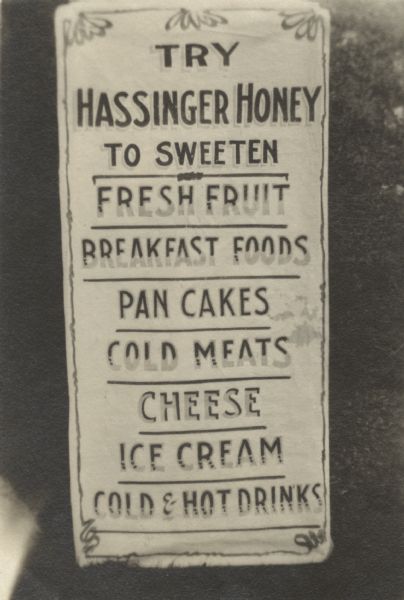 Sign reading "Try Hassinger Honey to sweeten fresh fruit, breakfast foods, pan cakes, cold meats, cheese, ice cream, and cold and hot drinks." Ed Hassinger, Jr. Greenville, WI.
