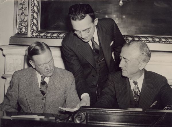 Arthur J. Altmeyer (center), Chairman of the Social Security Board, pictured as he appeared before the Senate Unemployment and Relief Committee. Altmeyer endorsed the principles of a broad program designed to increase and stabilize benefit payments to idle workers and needy dependents. Left is Senator Charles L. McNary (R-Ore), and right is Senator James F. Byrnes, D.S.C. Chairman.