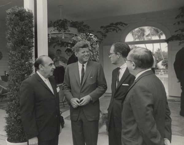 John F. Kennedy stands with Wilbur J. Cohen, turned away from the camera, right, and two unidentified men. This is may be around the time he signed the 1961 social security amendments into law.