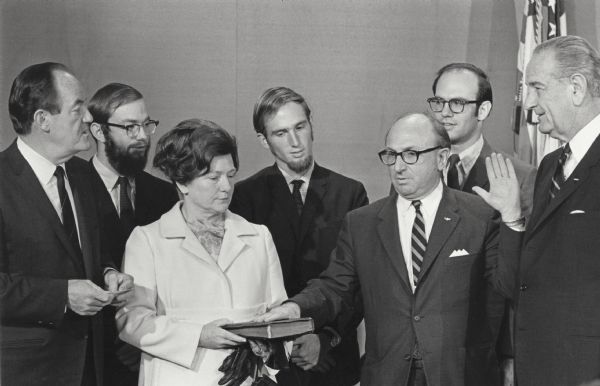 Wilbur Cohen raises his left hand as he is sworn in as Secretary of Health, Education and Welfare. Social Security was included in his responsibilities as part of Health, Education and Welfare. His wife, Eloise Cohen, holds the bible under his right hand. Vice-President Hubert Humphrey stands to her right; President Lyndon Johnson stands to Wilbur Cohen's left. In the second row are sons Stuart, Bruce and Chris Cohen.