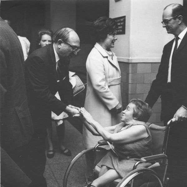 Wilbur J. Cohen receives comments from a woman in a wheelchair after his swearing-in as Secretary of Health, Education and Welfare. Among his responsibilities and achievements were Social Security and Medicare.