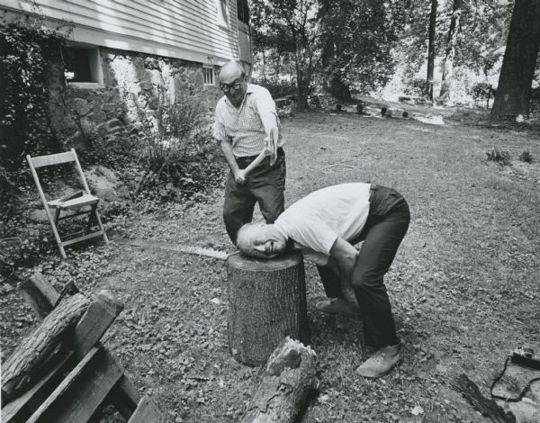 Wilbur J. Cohen holds an ax over his brother's neck. His brother has put his head on a log stump. The location is Wilbur Cohen's home in Silver Spring, Maryland.<p>Wilbur Cohen was a career public servant, helping to craft the Social Security Act when he was young, and eventually becoming the U.S. Secretary of Health, Education and Welfare.