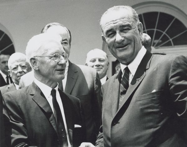 President Johnson gives a warm handshake to AFL-CIO Social Security Dir. Nelson H. Cruikshank after a White House ceremony in which he signed into law the Older Americans Act for research, development and training programs for the aged. Hubert Humphrey is standing behind Cruikshank.