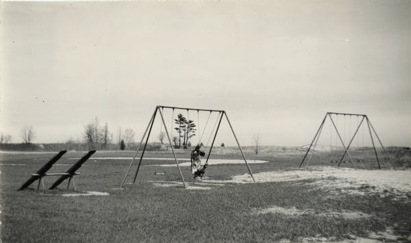Recreational grounds near the beach at Terry Andrae State Park. A woman and a child are on a swing set. There are teeter totters on the left.