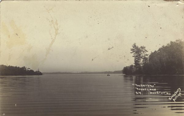 View across water of The Narrows in Trout Lake. There are people in a canoe out on the lake. Caption reads: "'The Narrows' Trout Lake, Wood Cliff, Wis."