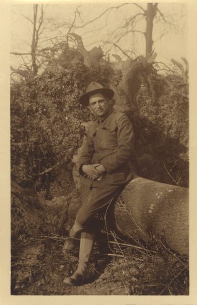 C.L. (Neal) Harrington leaning against a log somewhere in France.