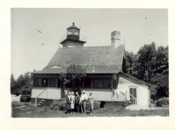 Group of people standing in the yard in front of the lighthouse. The verso has this annotation:<p>"'Eagle Light' Lighthouse, Peninsula Park, Fish Creek, Wis. This is where we stayed nights and for breakfast ate at Resorts."