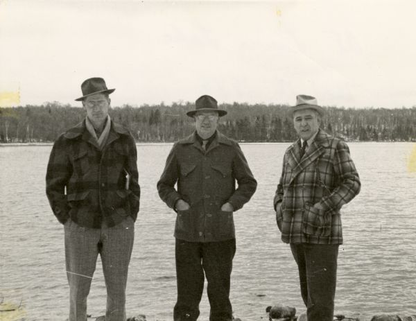 Three men, Mackie, Breuer, and Harrington, are standing in front of Laura Lake. The far shoreline is in the far background. Laura Lake was surveyed by the Wisconsin Conservation Department in 1941.