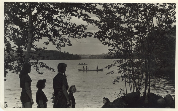 Exterior view of mile-long view of Lake Raymond (now known as Seventeen Lake), with several campers in foreground, and other campers in canoes on the lake. Original caption notes that view is from inside the lean-to, looking east.