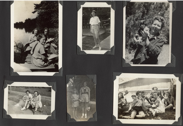 Page from Joy Camps photo album displaying six photographs. The one on the upper left shows three campers sitting in a rowboat along the shoreline sketching (with possibly another camper in the left foreground with her back to the camera); original caption notes that campers were "using flowers growing in the Bog Garden as subjects." Upper middle photograph shows a camper standing on a dock. Upper right photograph shows camp owner and co-director, Barbara Ellen Joy, holding a dog, near a wooded area; original caption notes: "Miss Joy holding the camp pet of 1943, by name of Jason." Lower right photograph shows campers eating outside, next to a building; original caption notes: "Members of the crackers 'n milk contingent busily at work in the middle of a fine afternoon." Lower middle photograph shows a younger, shorter camper standing next to an older, taller camper, each holding some sort of bag with strap; original caption notes: "The tall and the short of it in 1938." The lower left photograph shows two campers seated on the ground holding tennis rackets. One camper is wearing sunglasses (lenses are shaped like flowers).