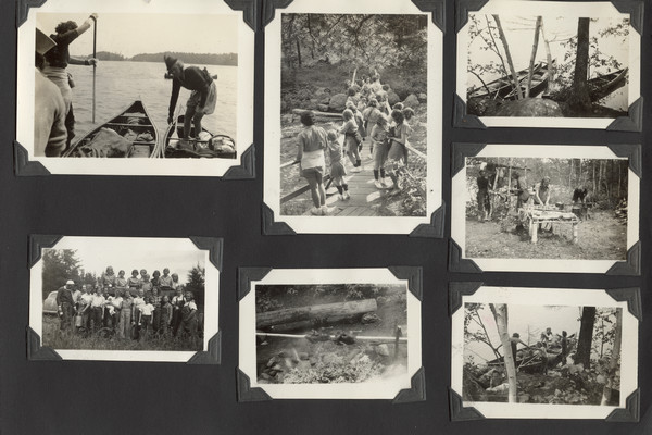 Page from Joy Camps photo album displaying seven photographs. Scenes depicted: canoes and campers on a lake; campers on a wooden footbridge; campers cooking out; and a large group of campers, several holding metal cups; one camper is holding a large, metal bucket (one of the campers is holding a baby; a car is in partial view in the background). Original caption notes: "A successful blue-berrying expedition about to start back to Camp. Blueberry pies, muffins and cake will be the reward." The caption also notes that the footbridge was over Cedar Falls along the Tomahawk River, "where we go each Fourth of July for a picnic." The cooking scenes are from Stumble Steps, "an old favourite camp site on Lake Kaubashine."