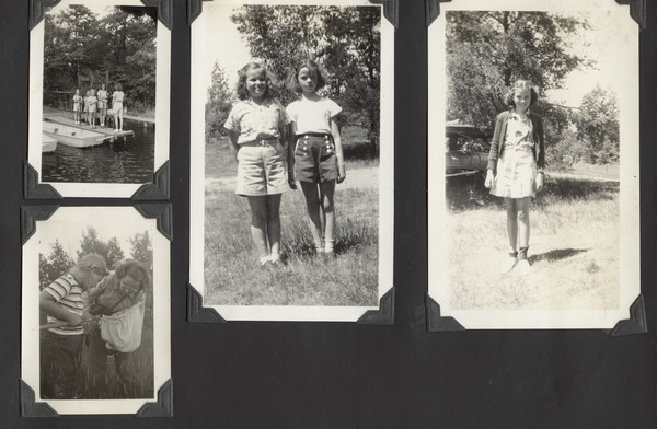 Page from Joy Camps photo album displaying four photographs of younger campers. In one photograph campers are standing on a dock near two boats. In two photographs campers are standing in grassy areas. In another photograph a woman and a camper peer into a fabric sack or net, perhaps intended for butterfly catching.