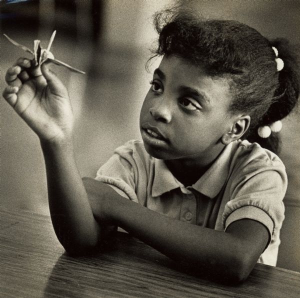 Melodie Albritton holds up an origami crane she folded at St. Nicholas School.