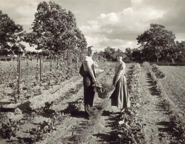 Alfred Lunt and Lynn Fontanne hold a basket of vegetables picked from their garden at Ten Chimneys.