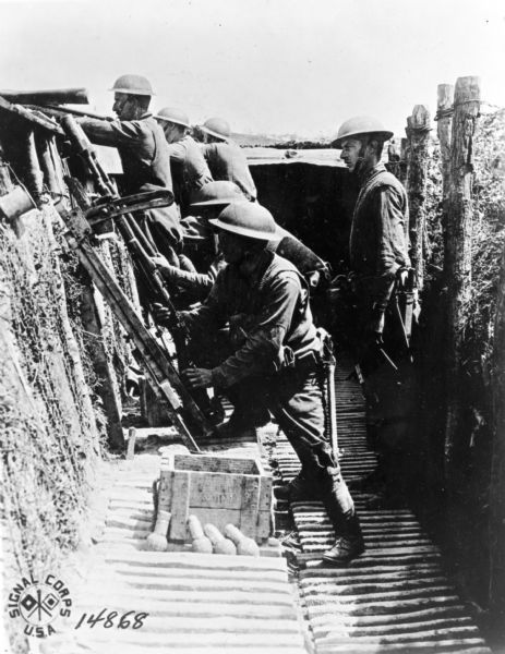 Soldiers with their weapons in a trench.