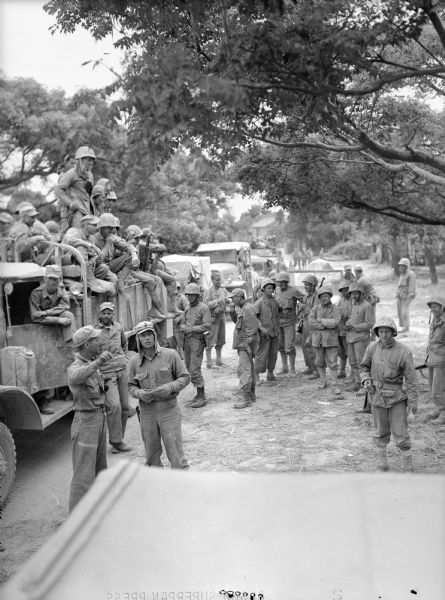 Several members of the 4th Marines, some standing in the road and others seated on vehicles at Ishikawa shortly after the city fell.