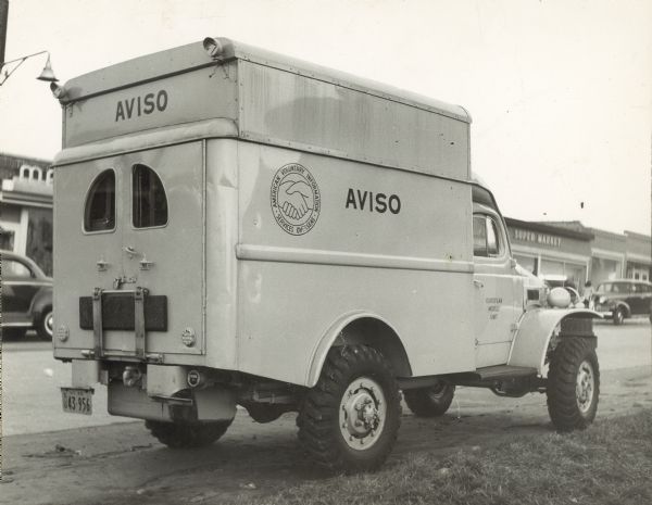 Three-quarter rear view from right of an American Voluntary Information Services Overseas (AVISO) truck parked outdoors.