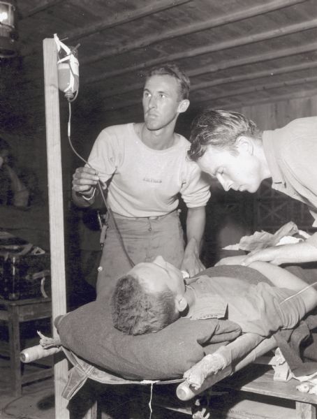 J.H. Price and another medic administer fluids to a wounded soldier through an intravenous tube at a field hospital in Okinawa.