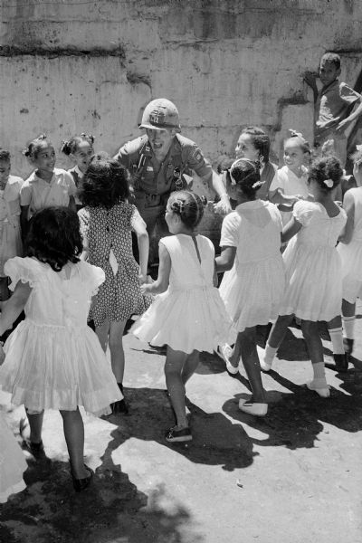 Paratroop Captain E.F. McGushin, Commander of Co. C, playing with 4th grade girls at recess in Santo Domingo, Dominican Republic.