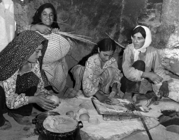 Women of the Hafezi family making bread with ingredients supplied by United States aid to Iran. One of the women weaves a basket.