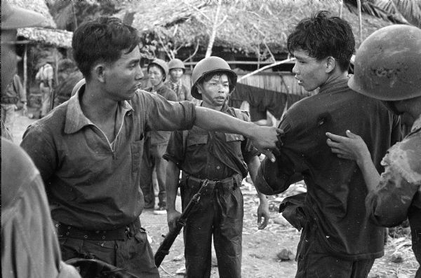 South Vietnamese medic inspects a wound on the shoulder of a Sea Swallow soldier at the village on Van Dinh.