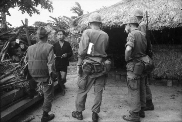 U.S. soldiers talk to a man in a Vietnamese village.