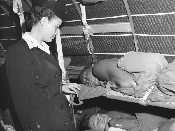 Flight nurse student checking on two patients sleeping in bunks.